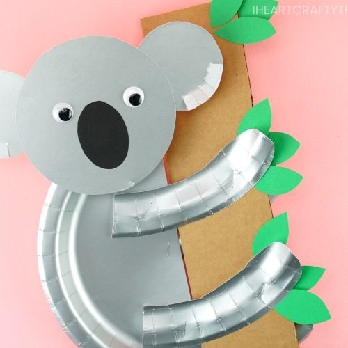 Koala craft made from paper plates hanging onto a paper bamboo tree