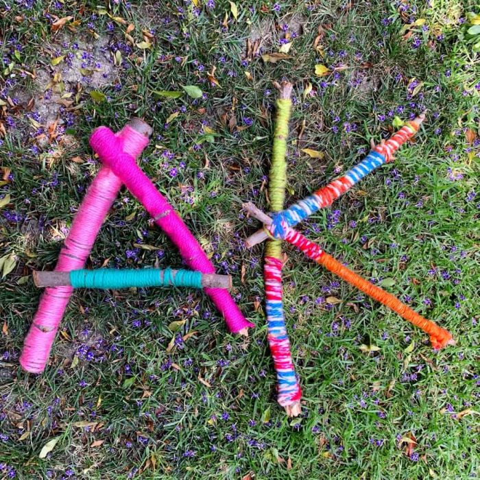 Large sticks wrapped in colorful yarn in shape of letters.