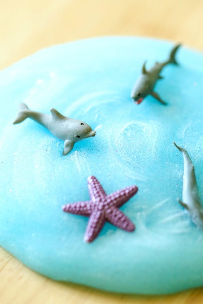 Blue sparkly slime with plastic ocean creatures swimming in it.