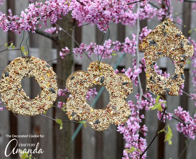 Multiple shaped birdseed ornaments hanging from a tree.