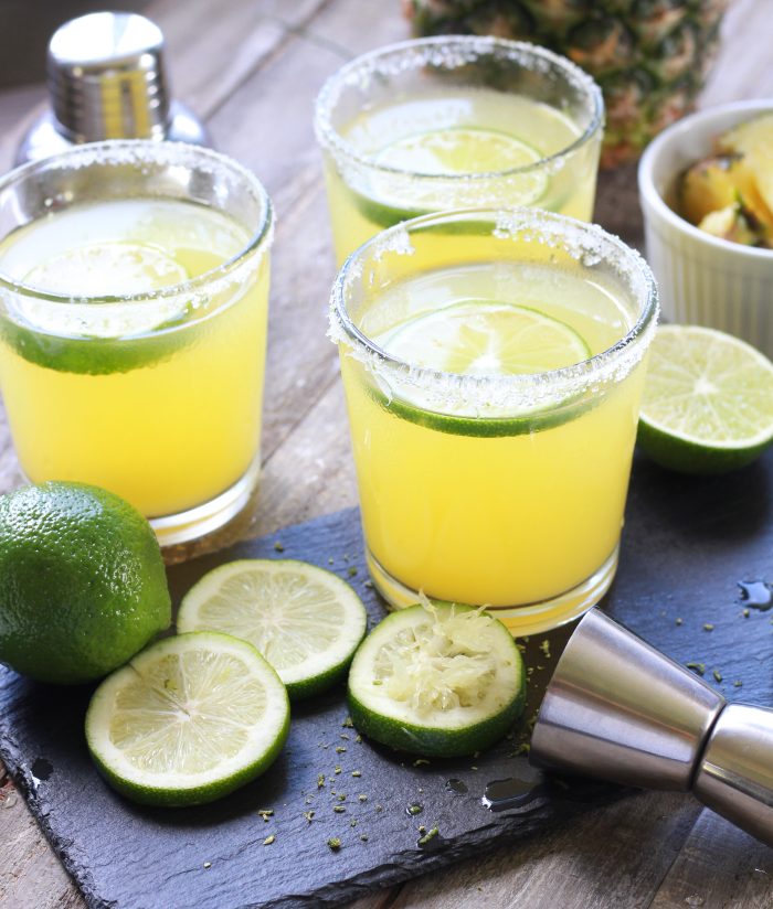 Three Pineapple Margaritas with sliced limes and fresh cut pineapple - Square Format