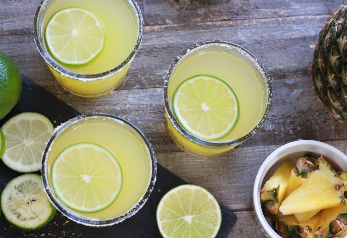 Three Pineapple Margaritas with sliced limes and fresh cut pineapple - Top down shot