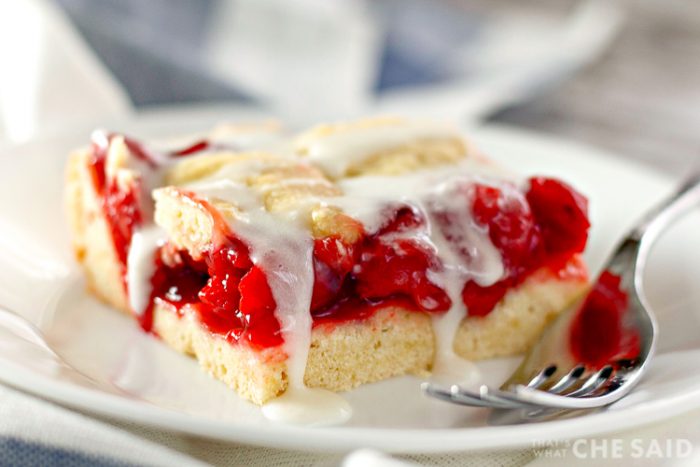 Close up of Cherry bar drizzled in frosting on a plate with fork