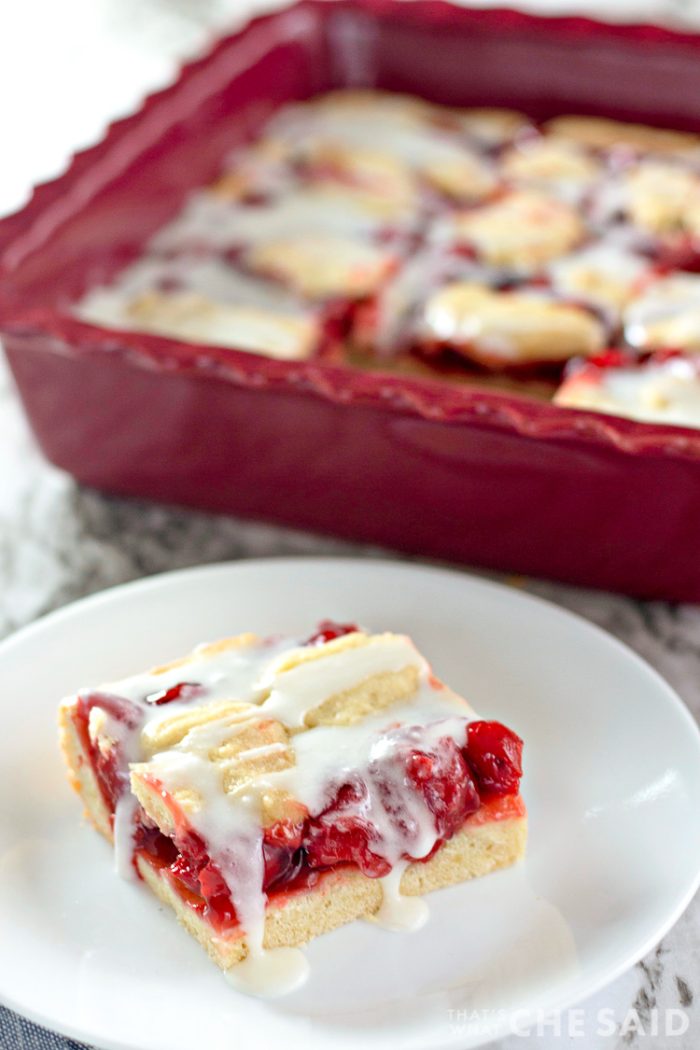 Cut cherry bar on white plate and pan of the rest in the background