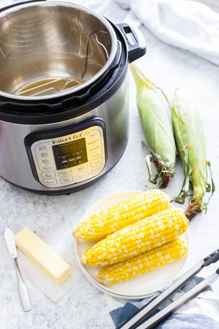 Corn on the cob on a plate with butter and instant pot in background 