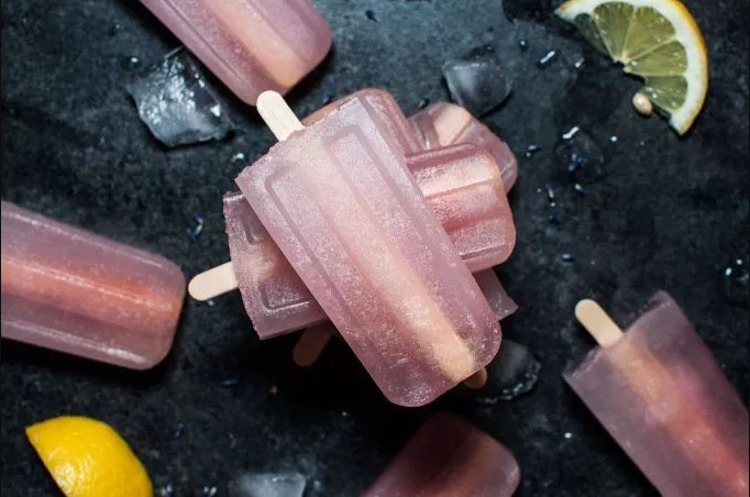 Lavender Lemonade Pops on black background with lemon wedges