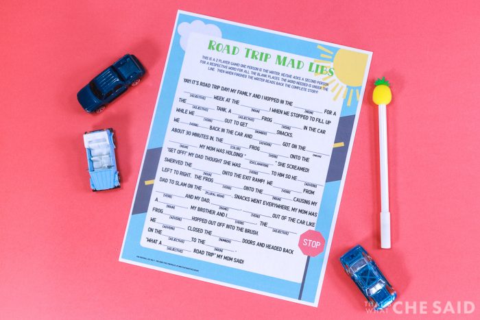 Coral background with Road Trip Mad Lib Printable and a pen and some matchbox cars Horizontal Format