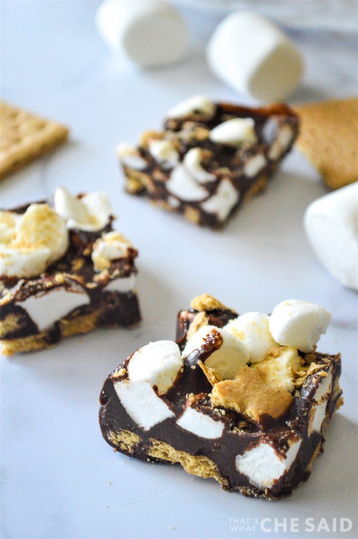 3 pieces of smore fudge with marshmallows and graham crackers in background