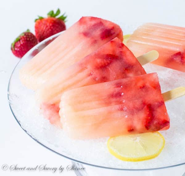 Strawberry Lemonade Popsicles stacked on a bowl of ice