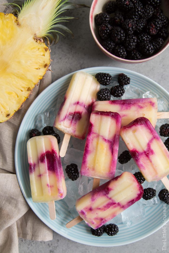 Balckberry Pineapple Pops in a bowl of ice. Pineapple and blackberries in sight