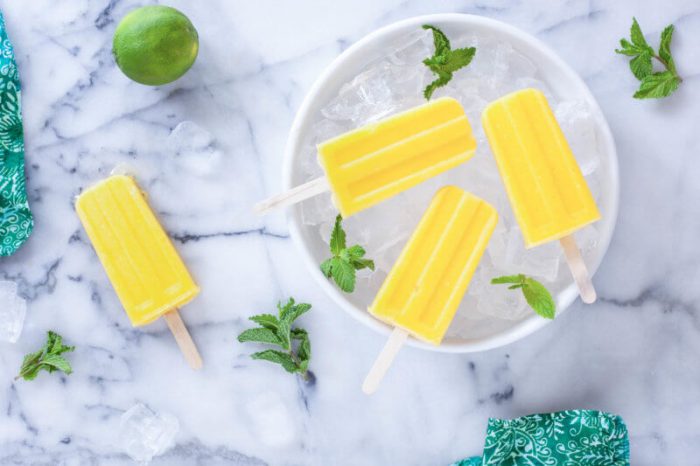 Mango Pineapple Popscicles laying on a bowl of ice