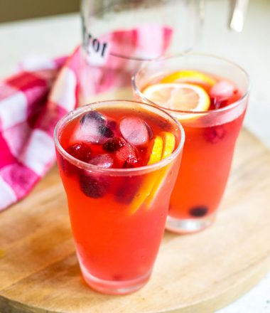 Two cups and a pitcher of finished berry lemonade.