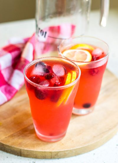 Two cups and a pitcher of finished berry lemonade.