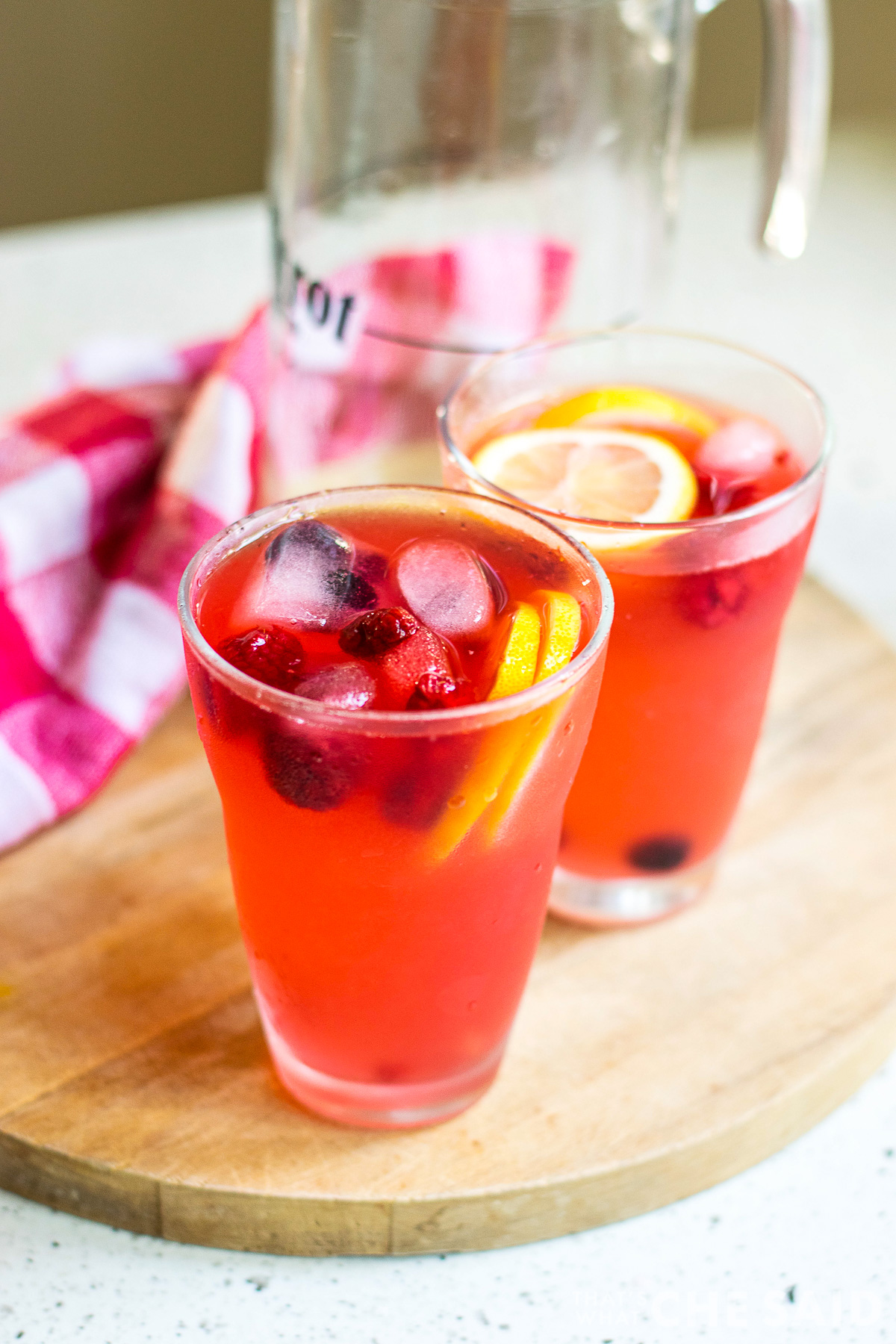 Two cups and a pitcher of finished berry lemonade.