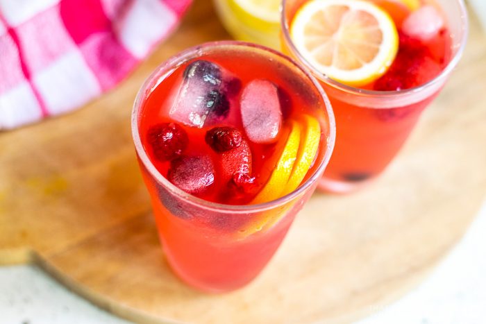 Close up of two cups filled with garnished berry lemonade.