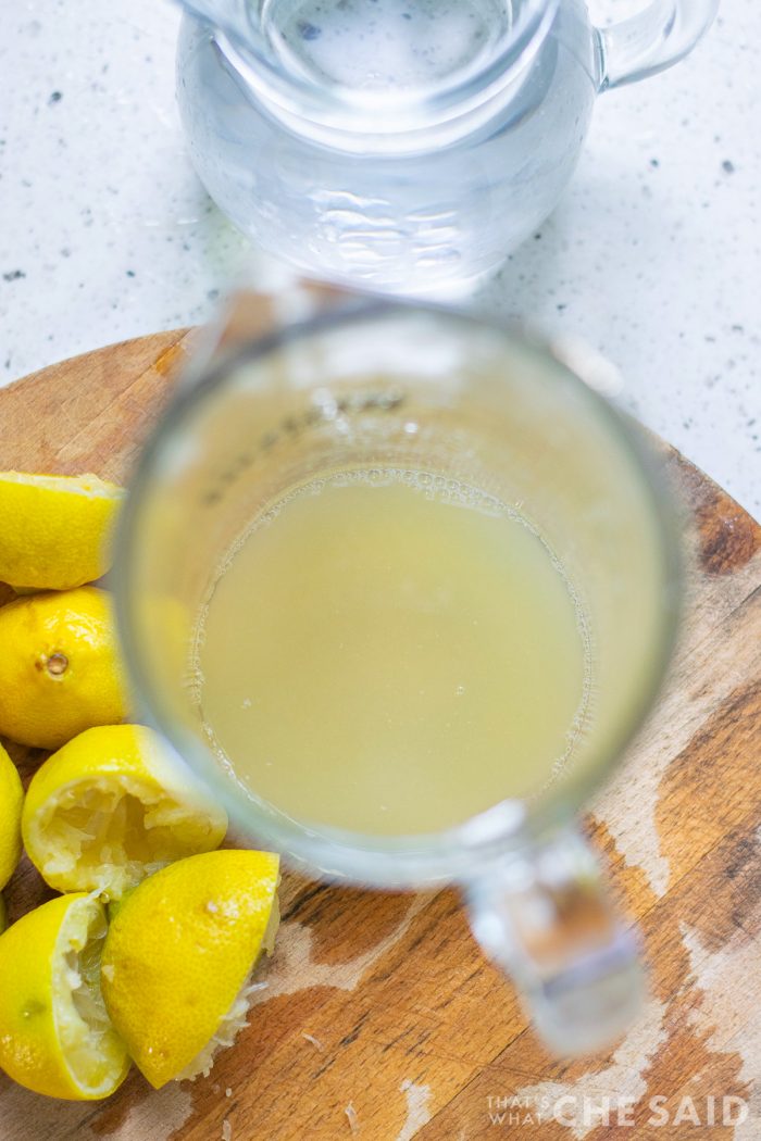 Overhead view of pitcher with lemon juice with the juiced lemons on the side.
