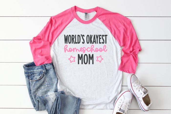White Raglan T-shirt with Pink sleeves and jeans and sneakrs. Shirt reads "World's Okayest Homeschool Mom" in iron on vinyl - Horizontal Format
