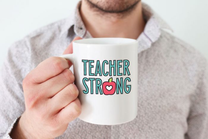 Man holding white coffee mug with "Teacher Strong" design in adhesive vinyl - horizontal format