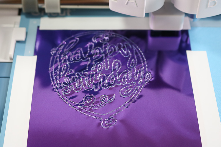 Close up of purple foil that has been pressed onto cardstock in the design of a happy birthday balloon