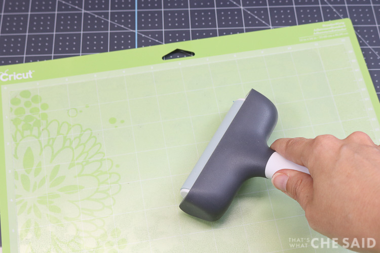 Using the Brayer to firmly adhere the plastic cutting mat from dollar sore onto to a 12x24 Standard Grip (green) mat