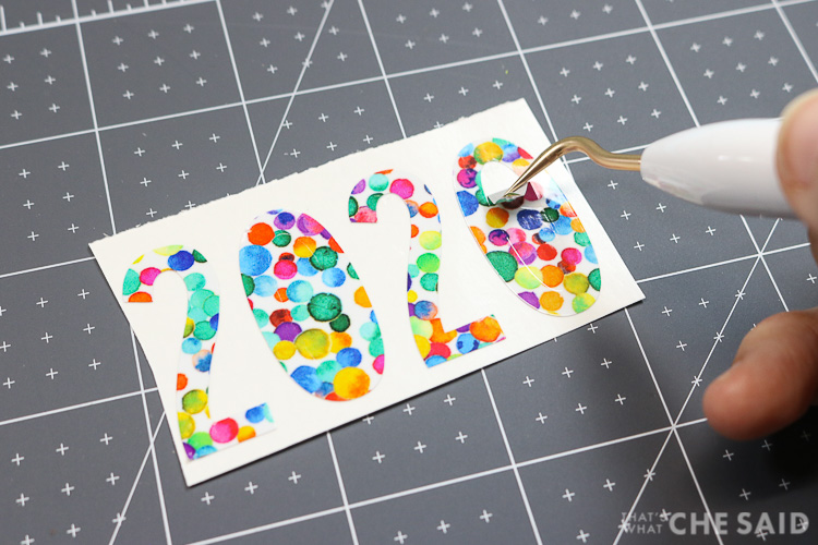 Using a weeding hook to remove the excess vinyl from the cut designs. Here I am removing the center of a zero