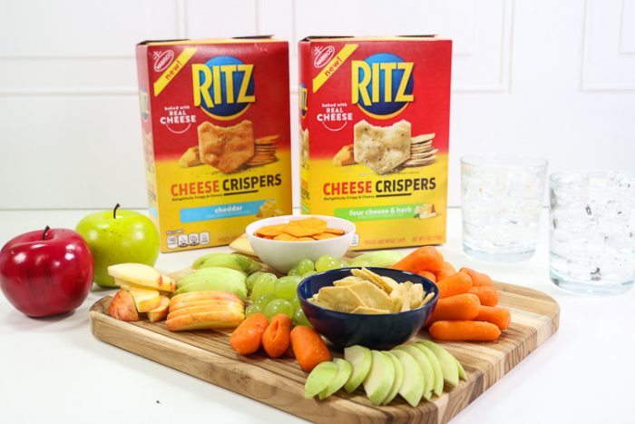 Overhead shot of board filled with fruit, veggies and Ritz Cheese Crispers with waters and horizontal