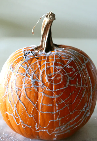 A pumpkin with hot glue and glitter spiderwebs