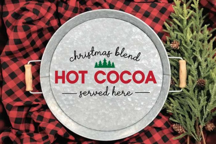 Galvanized Serving Tray with "Christmas Blend Hot Cocoa Served Here" SVG applied in adhesive vinyl on a red and black buffalo check blanket with some greenery in horizontal format