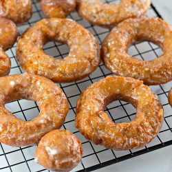 Pumpkin donuts and pumpkin donut holes on a black wire cooling rack