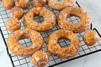 Pumpkin donuts and pumpkin donut holes on a black wire cooling rack