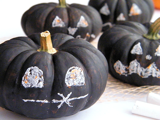 Pumpkins painted in black chalkboard paint and faces drawn on with chalk