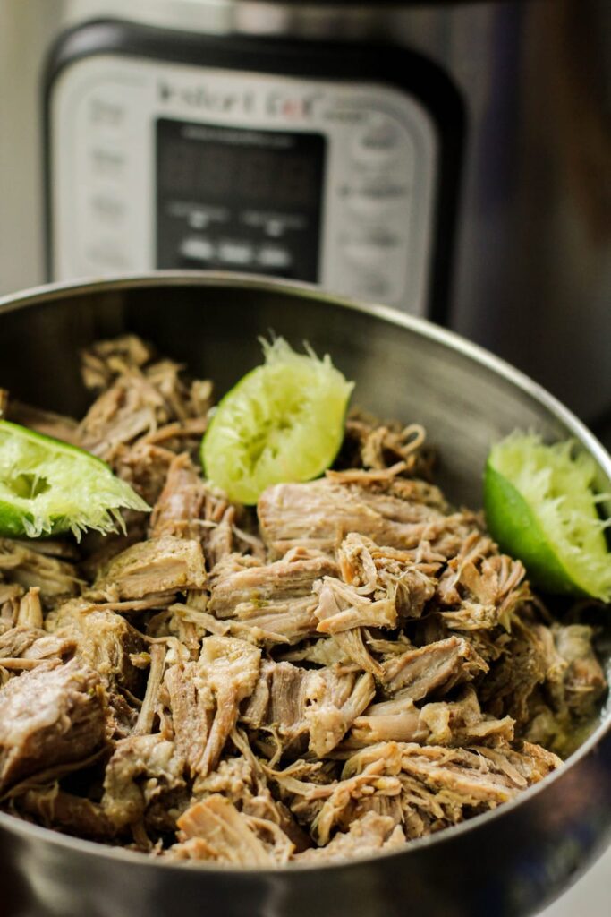 cuban pulled pork with lime in a bowl in front of instant pot
