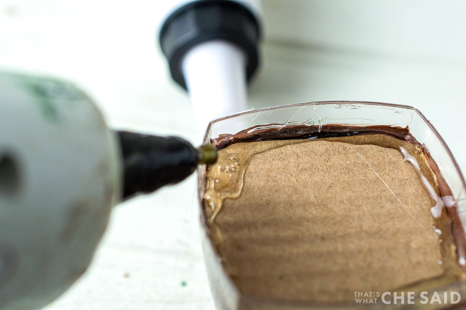 close up of hot glue gun gluing cardboard in place