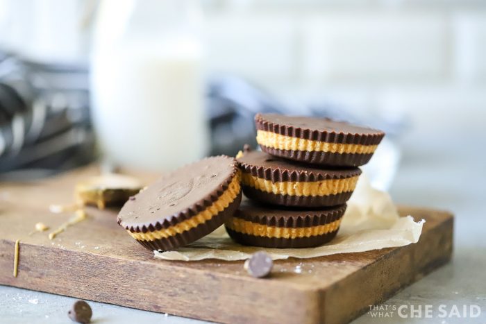 Close up of homemade peanut butter cups on small wooden board with milk in background