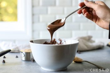 a woman holding a spoon of melted chocolate dripping back into a bowl