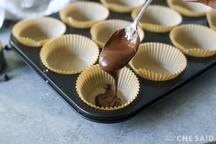 Pourcing melted chocolate into paper cupcake liners