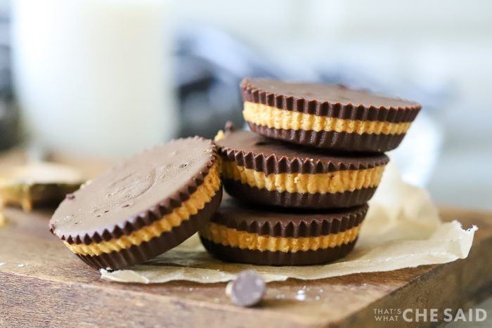 Homemade peanut butter cups on small board with parchment and extra chocolate chips around them