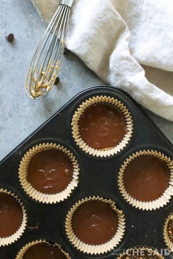 Cupcake tin with liners topped off with chocolate over peanut butter