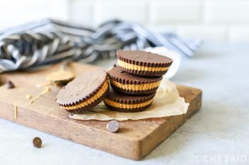 Finished peanut butter cups on small wooden board with towel in background