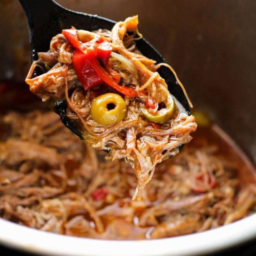 Serving spoon full of Cuban Ropa Vieja over the inner pot of the instant pot