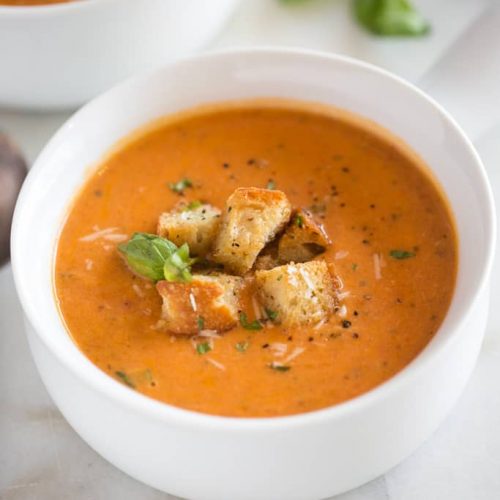 white bowl with tomato basil soup and croutons