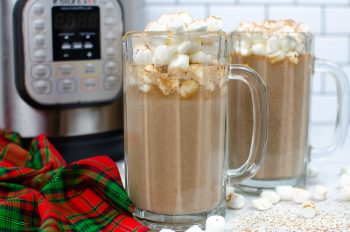 Horizontal view of Tuxedo Hot Chocolate in a tall glass mug with marshmallows on top. Another mug and Instant pot is in the background