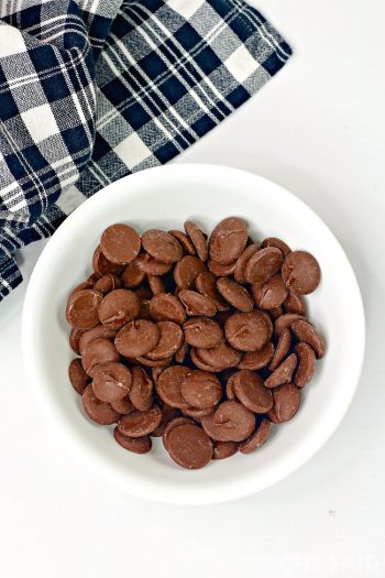 Melting chocolates in a white bowl with black plaid cloth napkin