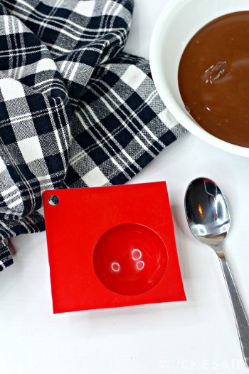 Bowl of melted chocolate and half sphere silicone mold and spoon