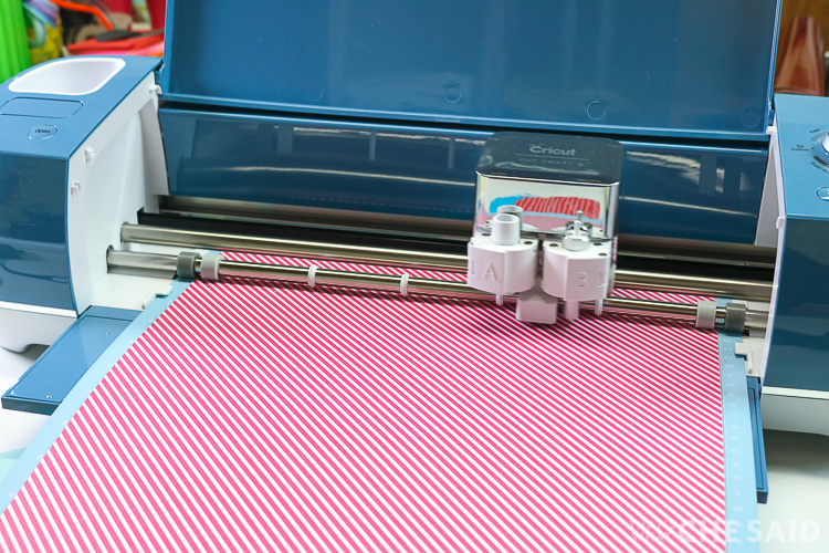 Denim colored Cricut Explore Air 2 cutting cardstock of white and pink diagonal lines