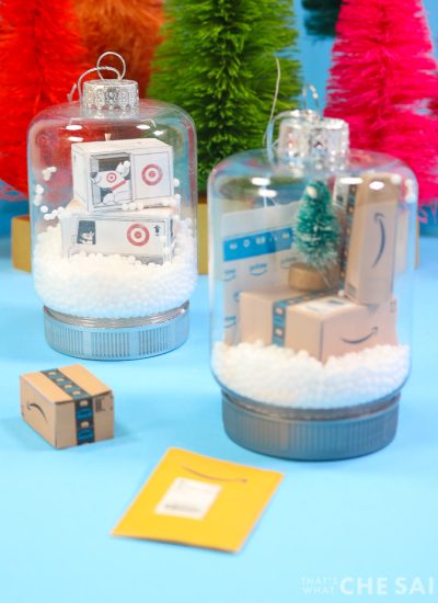 Two snow globe jar ornaments. One has miniature target boxes and one has miniature Amazon boxes and envelopes Vertical Orientation