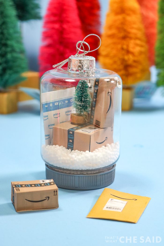 Two snow globe jar ornaments. Inside has fake snow and miniature Amazon boxes and envelopes