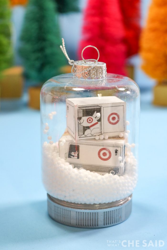 Two snow globe jar ornaments. One has miniature target boxes and fake snow