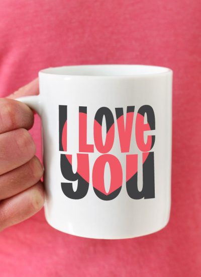 Man in pink shirt holding coffee mug with I love you block out design