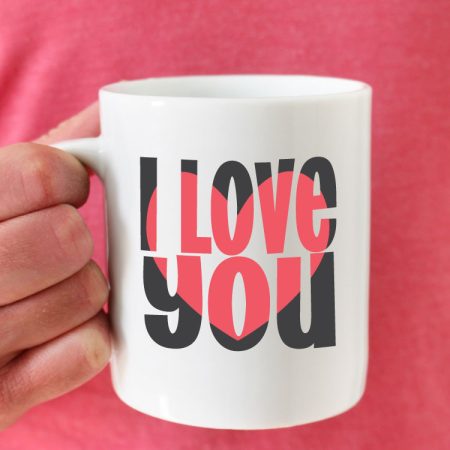Man in pink shirt holding coffee mug with I love you block out design